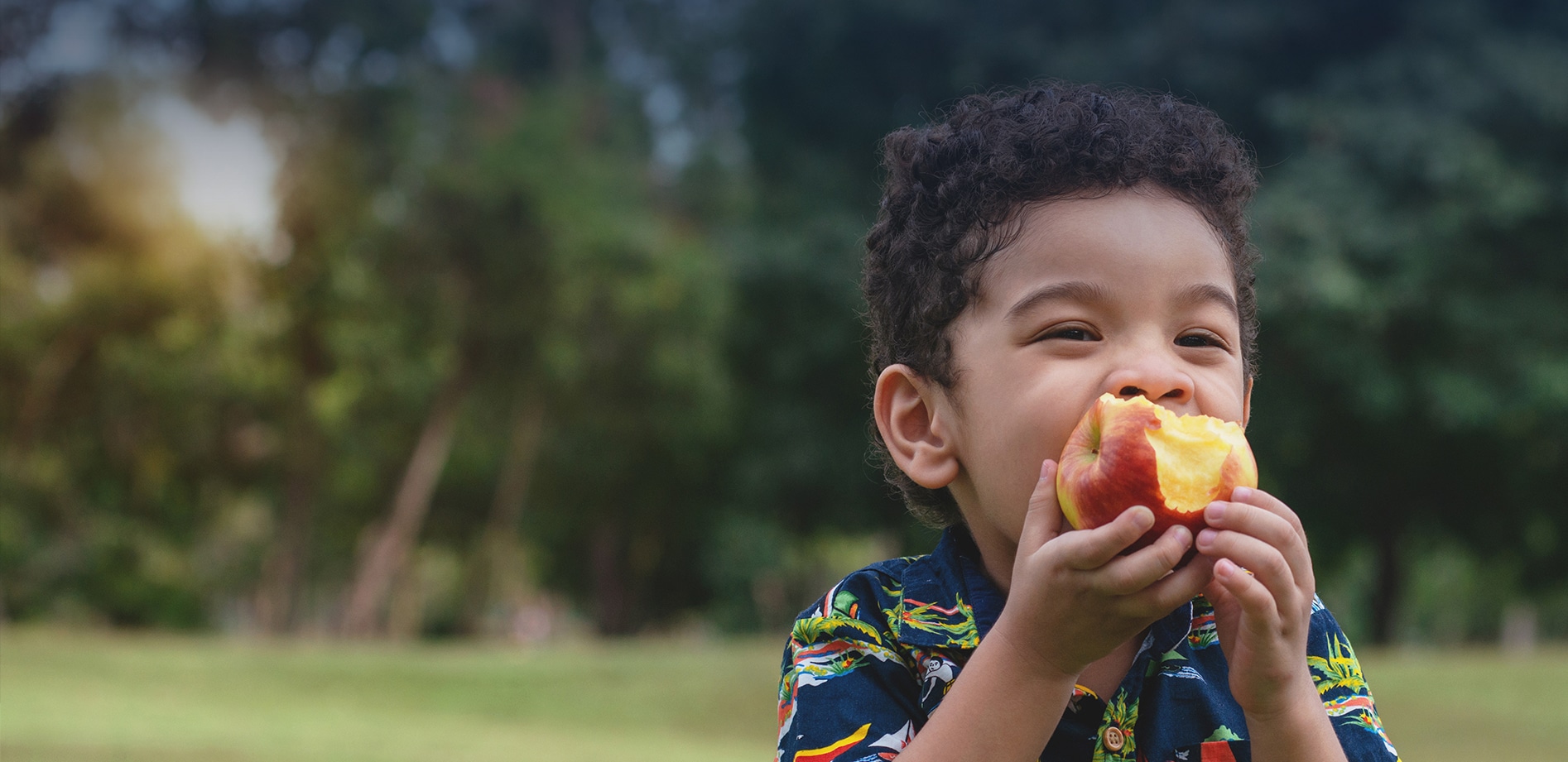 Child happily eating an apple, symbolizing health and nutrition support provided by Food Helpers